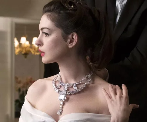 A woman in profile, wearing the Toussaint necklace from the movie "Ocean's 8," with elegant hair and a hand touching her shoulder.