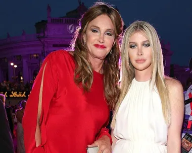 Caitlyn Jenner in red and Sophia Hutchins in white pose at a gala event with a lit building backdrop.