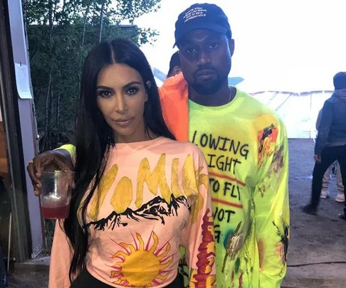 A man and woman wearing colorful shirts, the man wearing a cap, posing closely together outdoors.