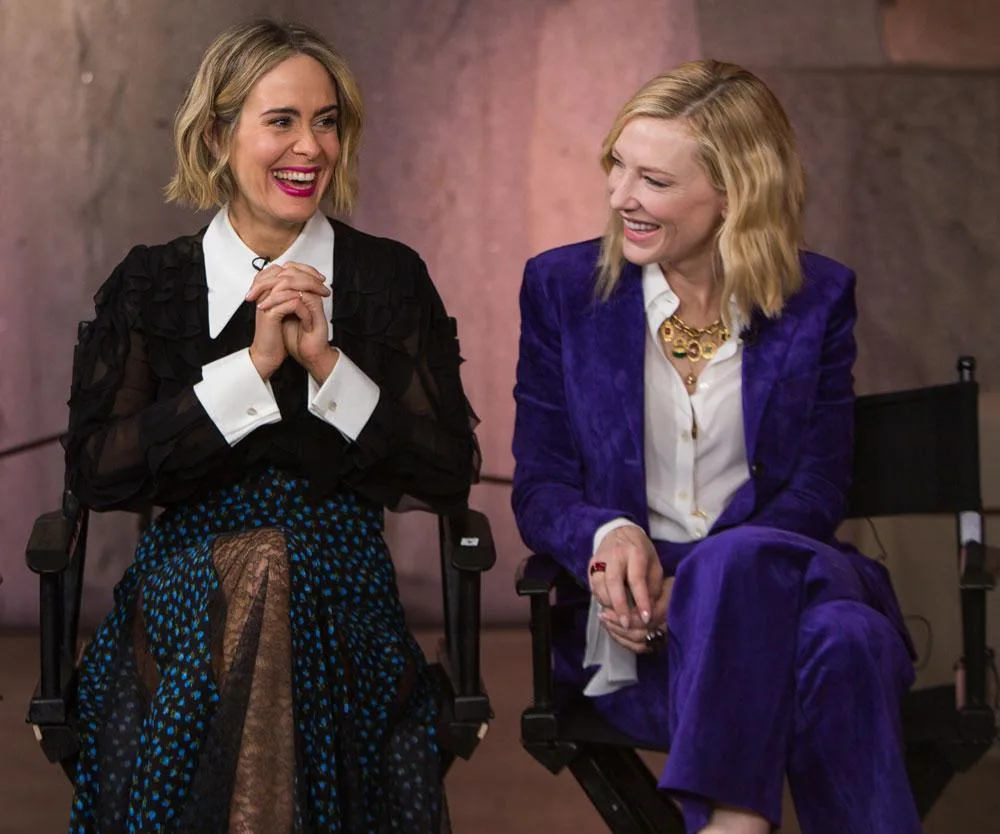 Sarah Paulson and Cate Blanchett during an interview for "Ocean's 8." Sarah wears black and white; Cate wears a purple suit.