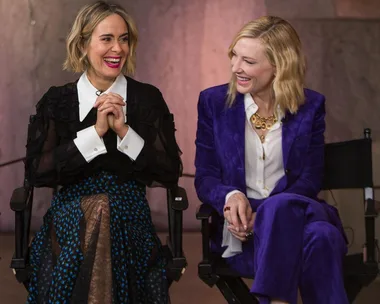 Sarah Paulson and Cate Blanchett during an interview for "Ocean's 8." Sarah wears black and white; Cate wears a purple suit.