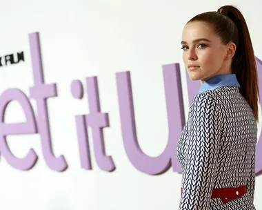 Zoey Deutch poses in front of a "Set It Up" promotional backdrop.