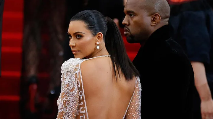 Kim Kardashian and Kanye West pose together on a red carpet, with Kardashian in a backless dress.