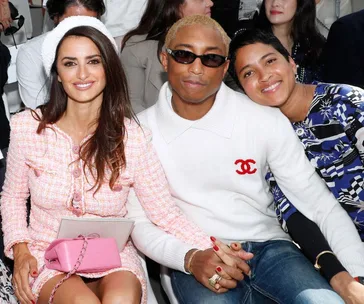 Group seated in front row at Chanel Couture show, with the person in white wearing sunglasses and a Chanel sweater.