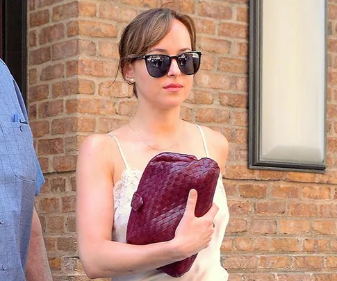 Dakota Johnson walks through the airport with sunglasses on