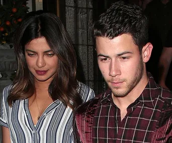 Priyanka Chopra and Nick Jonas walking together outdoors, both looking down.