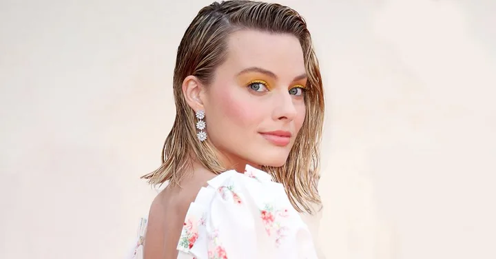 Margot Robbie as Sharon Tate with wet hair, floral dress, and yellow eye makeup.