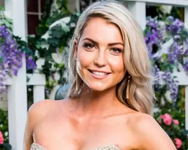 Shannon from The Bachelor Australia 2018, posing in a strapless dress, smiling in front of a floral background.