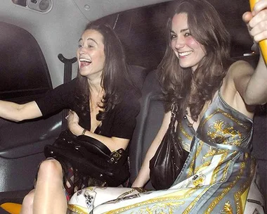 Two women smiling and laughing inside a car, one wearing a patterned dress and the other holding a handbag.