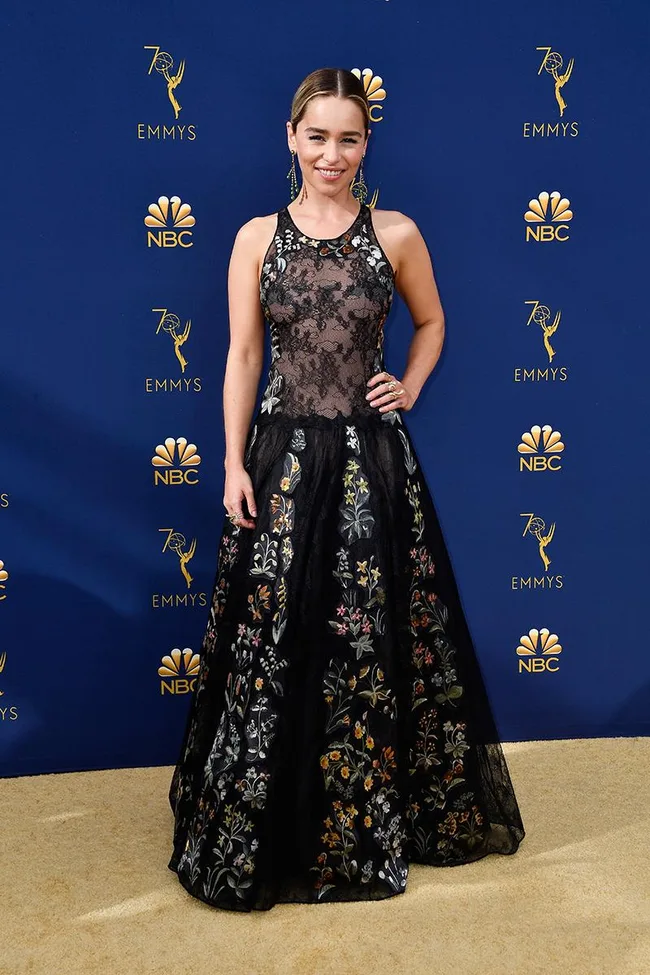 Woman in a floral gown at the 70th Emmy Awards, standing on a gold carpet with a blue background featuring NBC logos.