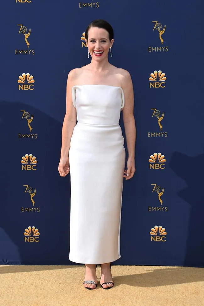 A woman in a strapless white dress poses at the 70th Emmy Awards with NBC logos in the background.