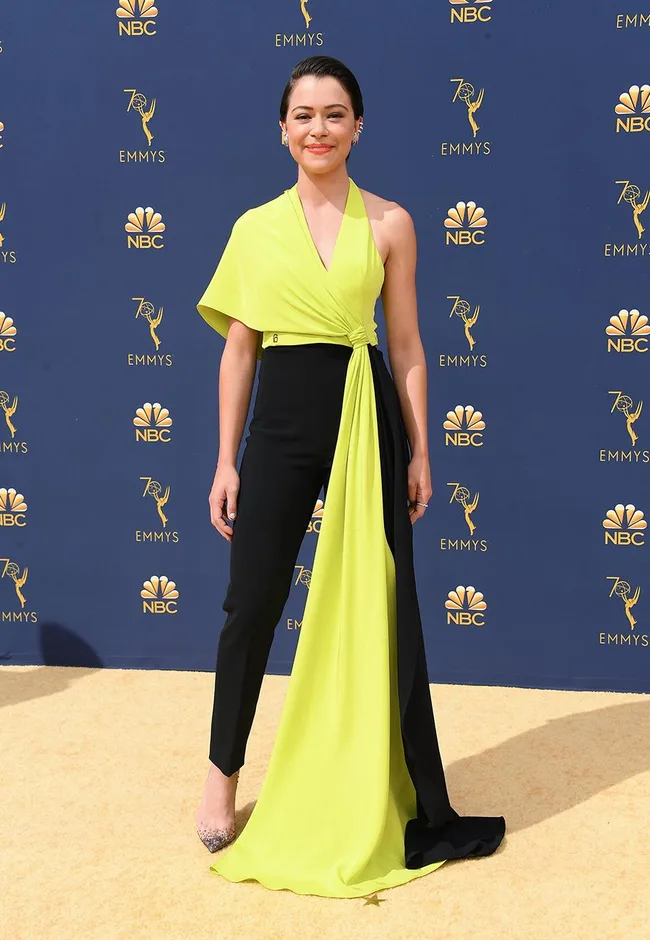 A person in a lime green and black outfit poses on the red carpet at the 70th Emmys.