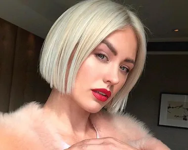 A woman with a platinum blonde bob, red lipstick, wearing a pink fur coat.