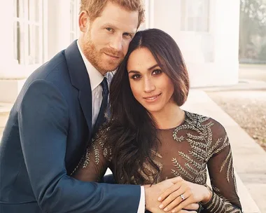 A couple embracing, the woman showing an engagement ring on her hand resting on the man's arm.