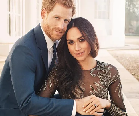 A couple embracing, the woman showing an engagement ring on her hand resting on the man's arm.