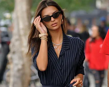 Woman in pinstripe dress and sunglasses walking down a city street.