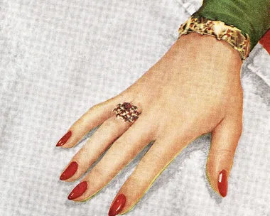 A hand with red nail polish, a jeweled ring, and a gold bracelet on a white background.