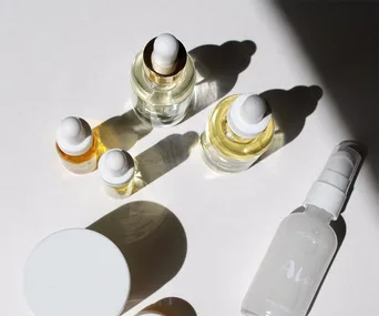 Various luxury skincare serum bottles arranged on a light surface.