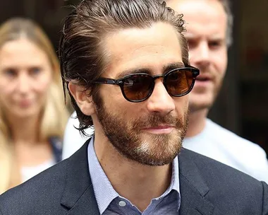 Man with sunglasses, thick beard, slicked-back hair in a suit.