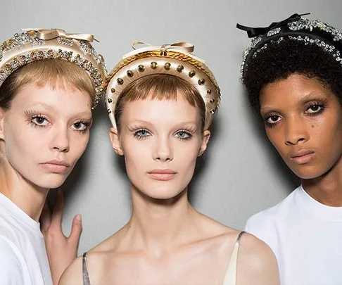 "Three models wearing embellished headbands with neutral makeup against a plain background."