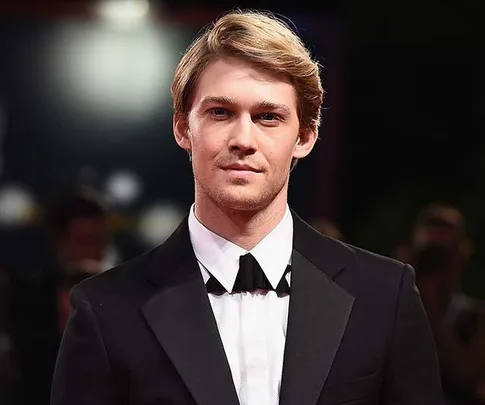 Joe Alwyn in a black tuxedo on the red carpet at a formal event.