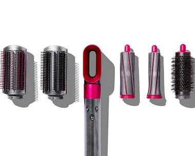 Dyson Airwrap styler and its five attachments including two barrels, two smoothing brushes, and a round volumizing brush.