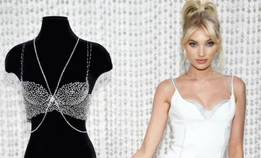 Elsa Hosk in a white dress standing next to a mannequin wearing the Victoria's Secret Fantasy Bra.