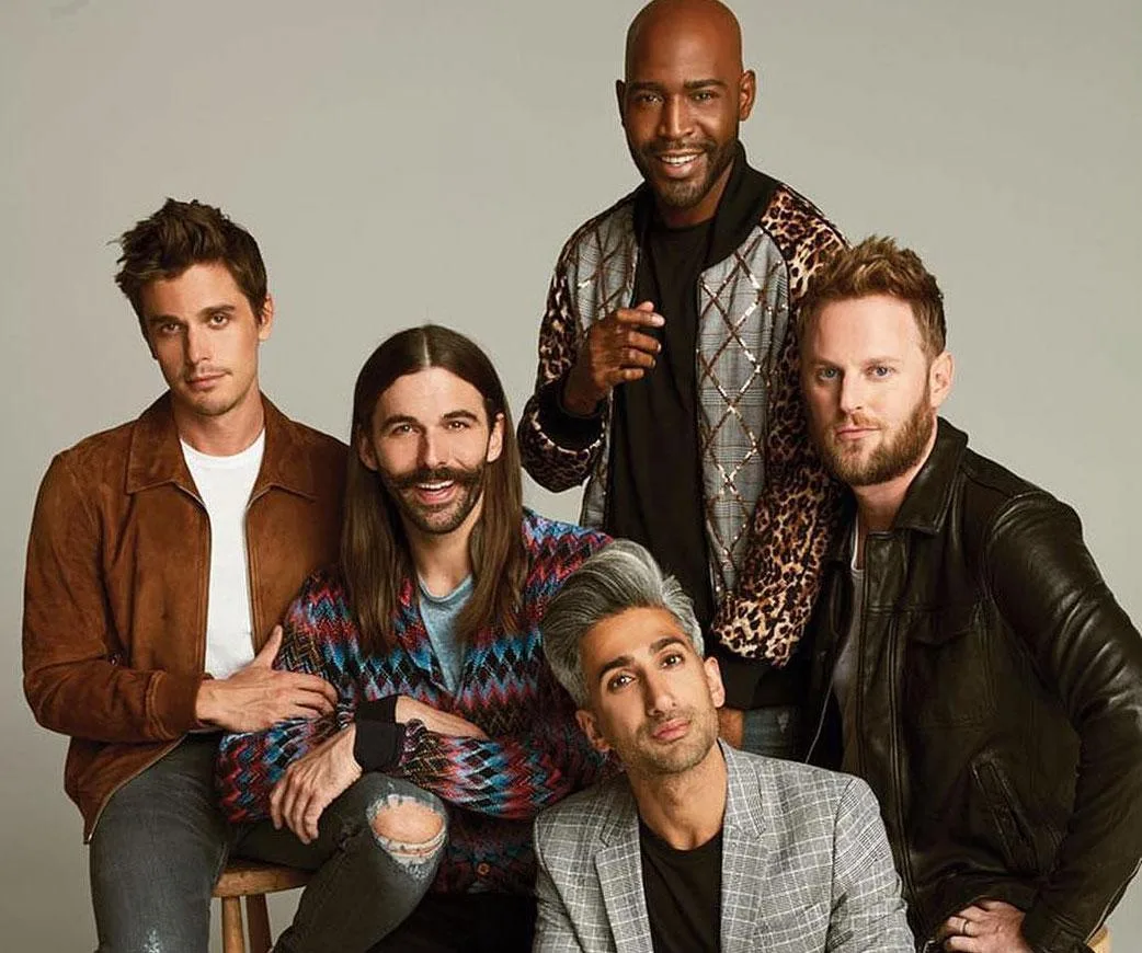 "Queer Eye's Fab Five posing together: Antoni, Jonathan, Karamo, Tan, and Bobby, dressed stylishly against a plain backdrop."