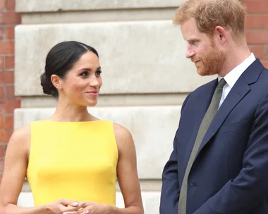 A woman in a yellow dress and a man in a suit standing together, exchanging smiles.