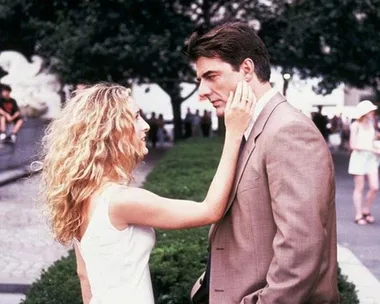 Carrie Bradshaw touching Mr. Big's face in a park from "Sex and the City".