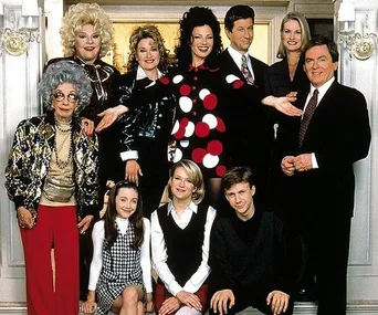 Cast of "The Nanny" posing in formal attire inside an elegant room, with ornate decorations in the background.