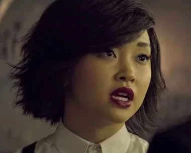 Lana Condor's character Saya Kuroki with short hair, intense expression, and dark lipstick in a scene from "Deadly Class."