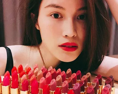 Woman with red lipstick surrounded by assorted lipsticks.