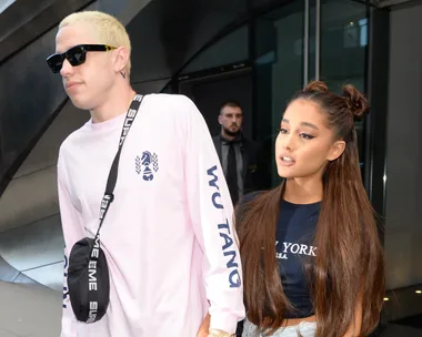 Pete Davidson and Ariana Grande walking together, with Davidson in sunglasses and Grande with double buns and long hair.