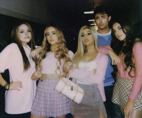 Ariana Grande in "Mean Girls" tribute scene from "Thank U, Next" video, surrounded by cast dressed in pink outfits.