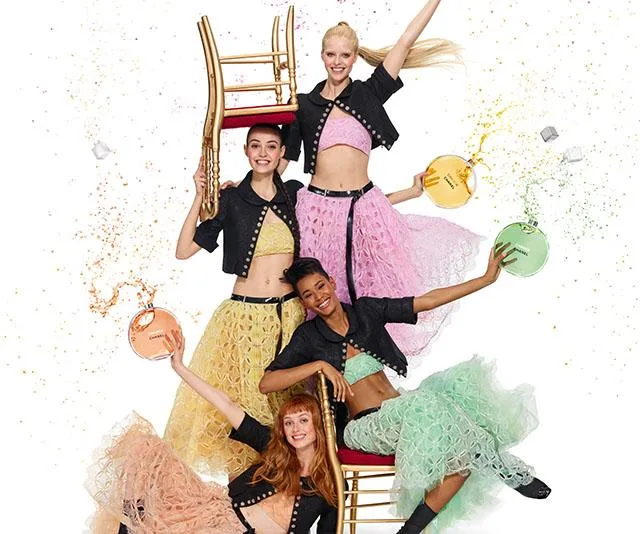 Four women in colorful skirts joyfully pose with Chanel Chance Eau Tendre perfume bottles, exuding playful energy.
