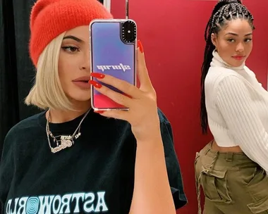 Two women pose in a mirror selfie. One wears a red hat and holds the phone; the other stands in a white sweater.