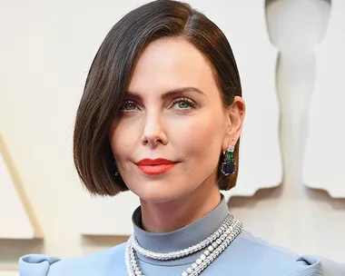 A woman with a sleek bob haircut, bold red lipstick, and diamond jewelry at an event.