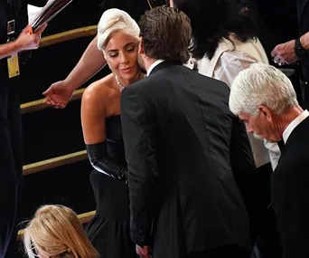 Lady Gaga and Bradley Cooper in formal attire share a moment at the 2019 Oscars.