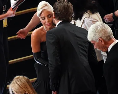 Lady Gaga and Bradley Cooper in formal attire share a moment at the 2019 Oscars.