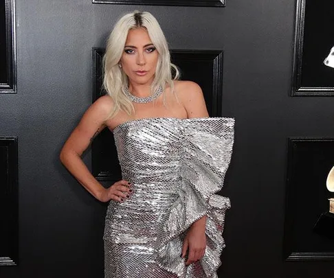 Lady Gaga in a silver sequined dress at the Oscars 2019, posing on the red carpet.