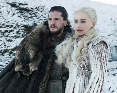 Two characters from "Game of Thrones" standing in a snowy landscape, dressed in fur and winter attire.