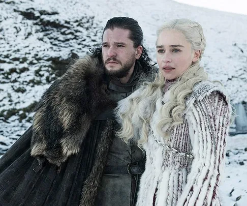 Two characters from "Game of Thrones" standing in a snowy landscape, dressed in fur and winter attire.