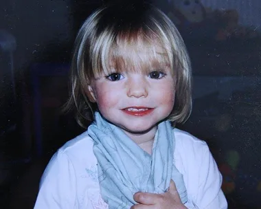 Young child with short blonde hair smiling, wearing a light blue scarf and white shirt.