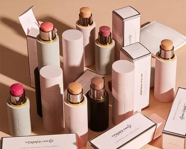 Collection of Westman Atelier makeup sticks and packaging arranged on a neutral background.