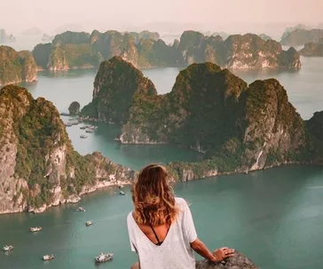 Woman overlooking Ha Long Bay, Vietnam, with boats and limestone islands in the background.