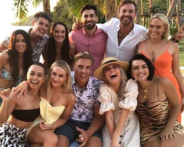 Group photo of Bachelor in Paradise Australia 2019 contestants smiling outdoors, with tropical backdrop.