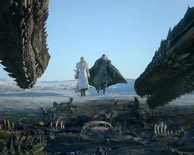 Daenerys and Jon Snow walking towards two dragons in a snowy landscape.