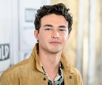 Young man with tousled hair wearing a tan jacket, standing in front of a backdrop with Build Series logo.