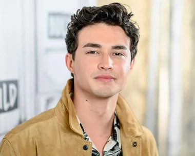 Young man with tousled hair wearing a tan jacket, standing in front of a backdrop with Build Series logo.